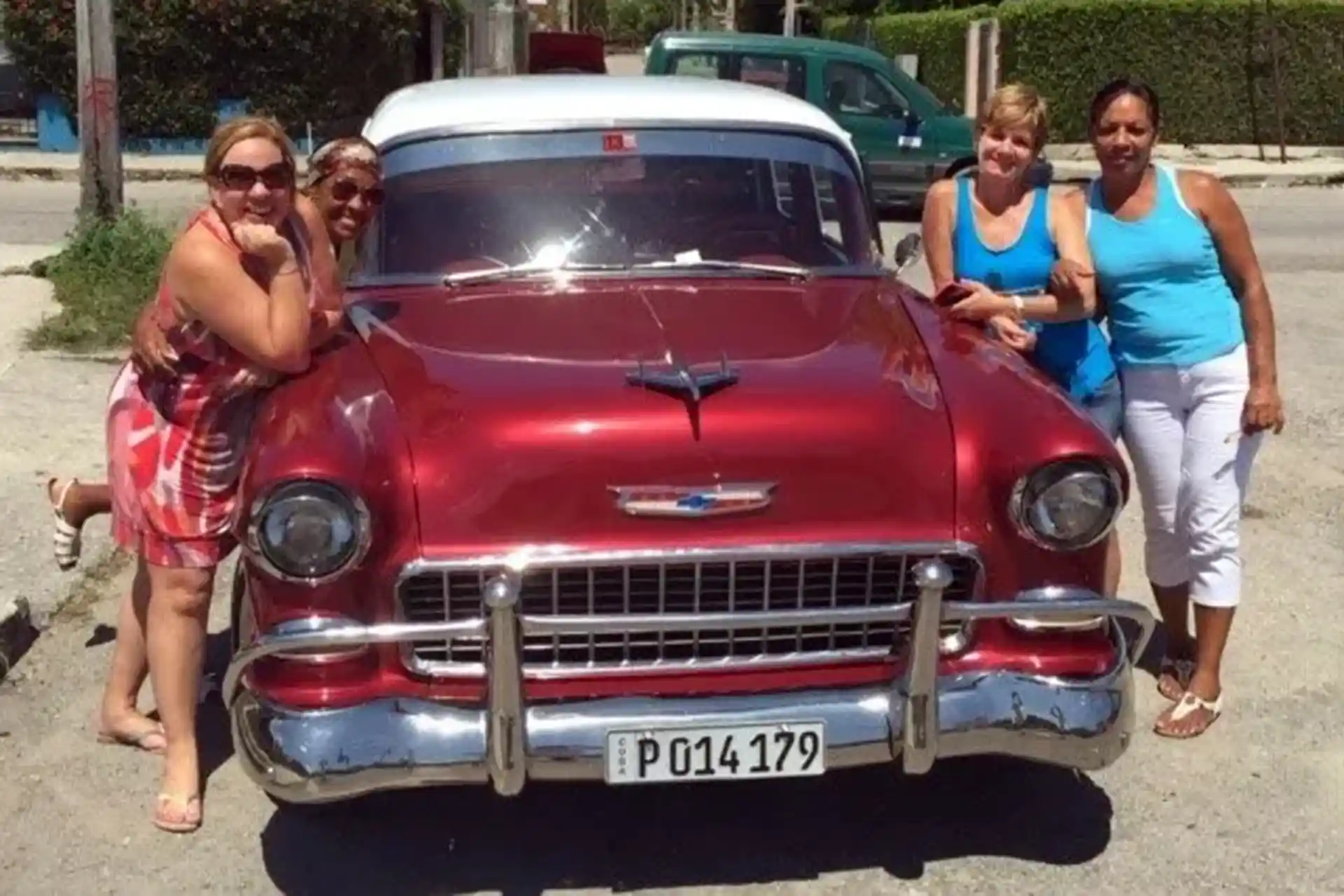 Four ladies in front os a red 1955 Chevy Belair car
