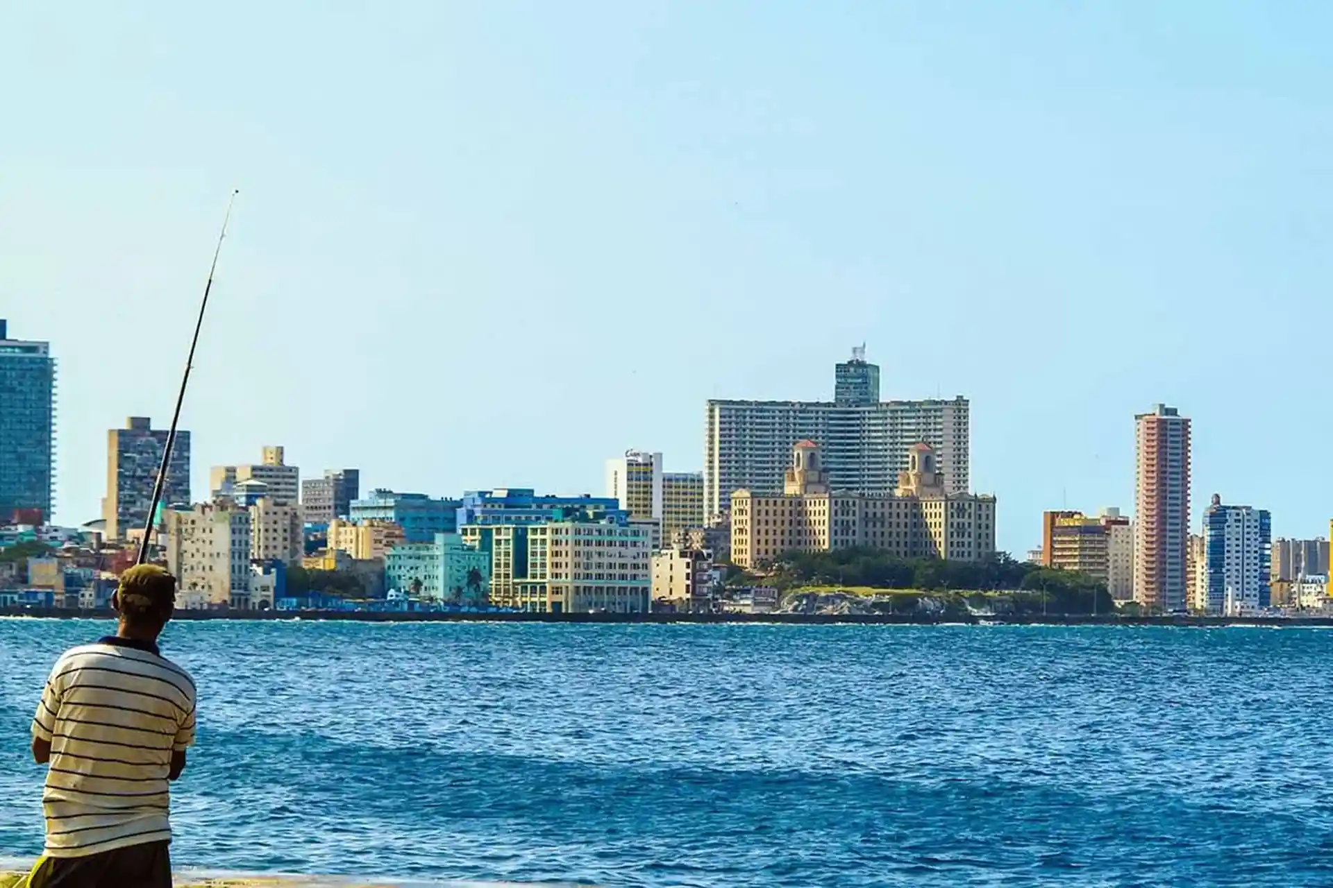man fishing in Havana Bay with buildings far away